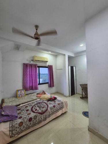 a bedroom with a bed and a ceiling fan at Serene Farmhouse in Nimarkheri