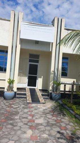 a white building with a door and a palm tree at Maisara lodge in Kilindoni