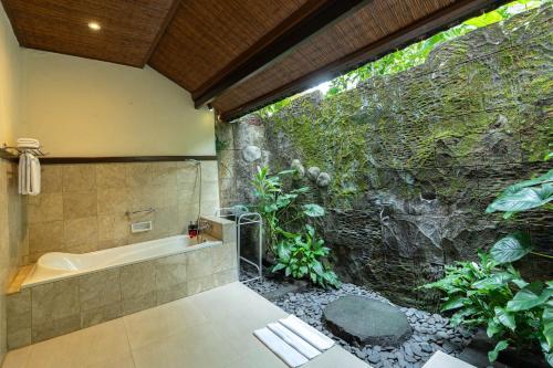 a bathroom with a large stone wall and a bath tub at Ananda Ubud Resort in Ubud