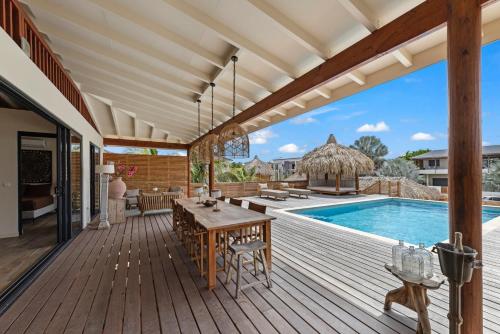 an outdoor deck with a table and a pool at El Patrón, the villa in Jan Thiel