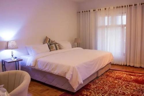 a bedroom with a large white bed and a window at Kutenga Guest House in Maputo