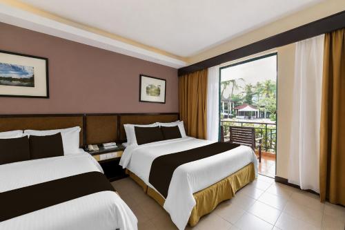 two beds in a hotel room with a balcony at Sunday Residence Inn Cherating in Cherating