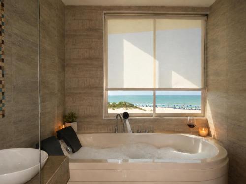 a bathroom with a tub and a window with the beach at Hotel Summer Frente Al Mar in Cartagena de Indias