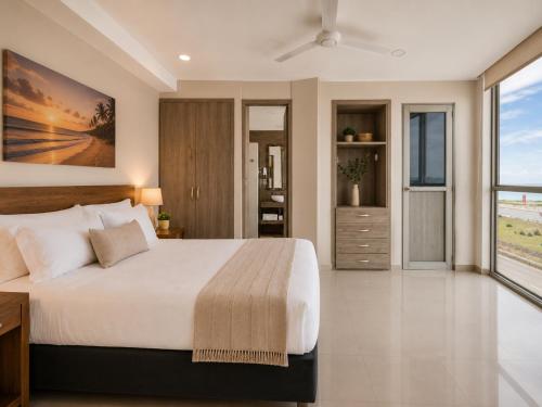 a bedroom with a large bed and a large window at Hotel Summer Frente Al Mar in Cartagena de Indias