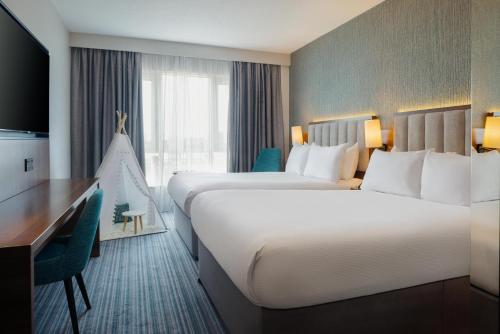 a hotel room with two beds and a desk at DoubleTree by Hilton London Chelsea in London