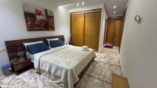 a bedroom with a large bed with blue pillows at Airport's Layover Apartment in Nouaceur