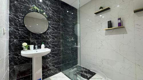a black tiled bathroom with a sink and a mirror at Airport's Layover Apartment in Nouaceur