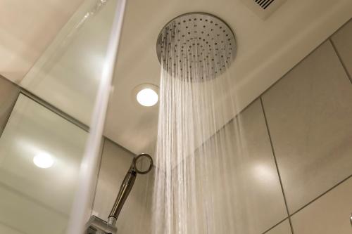 a shower with a shower curtain in a bathroom at KOKO HOTEL Sapporo Susukino 2ⁿᵈ in Sapporo