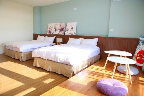 a bedroom with two beds and a table and a stool at Mulin B&B in Hengchun