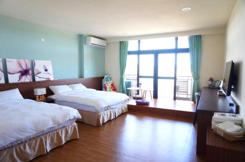 a hotel room with two beds and a large window at Mulin B&B in Hengchun