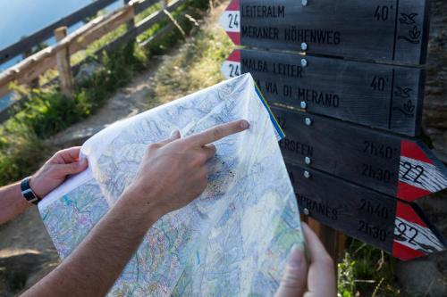 a person holding a map in front of a sign at Hotel Garni Vigilhof in Lana