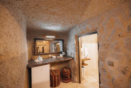 a bathroom with a mirror and a stone wall at Velum Cappadocia in Göreme
