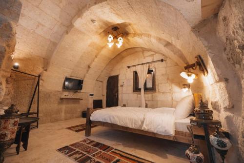a bedroom with a bed in a stone wall at Velum Cappadocia in Göreme