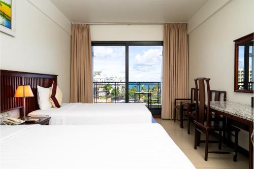 a hotel room with two beds and a balcony at Praha Hotel Phú Quốc in Phú Quốc