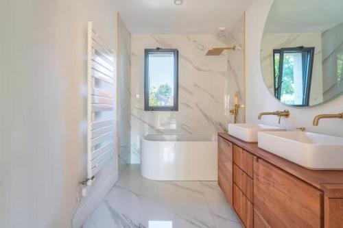 a bathroom with two sinks and a tub and a mirror at House Moringa Rituals Pool in Le Plessis-Trévise