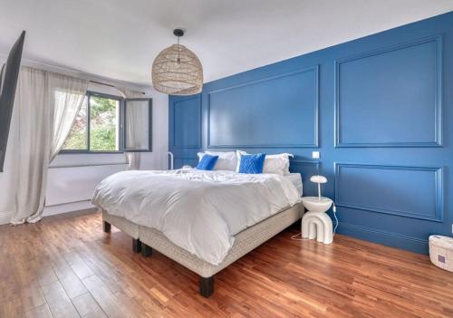 a blue bedroom with a large bed and a window at House Moringa Rituals Pool in Le Plessis-Trévise