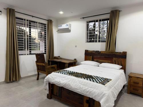 a bedroom with a large bed and two windows at 2BR Apartment in Tanga in Tanga