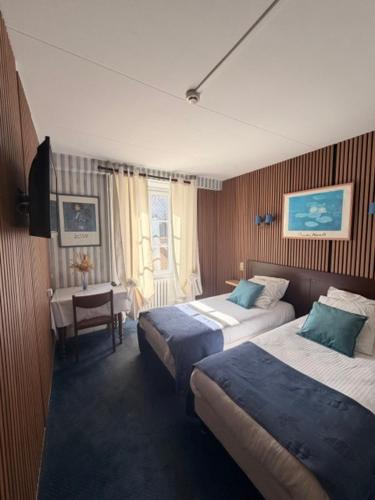 a hotel room with two beds and a table at Hotel De Paris in Poligny