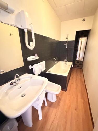 a bathroom with a sink and a bath tub at Hotel De Paris in Poligny