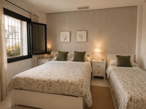 a bedroom with two beds and a window at Hostal Baobab in El Puerto de Santa María