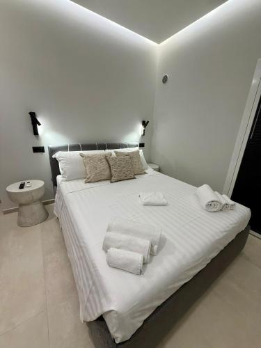 a white bedroom with a large bed with towels on it at H Luxury Apartment Crispi in Olbia