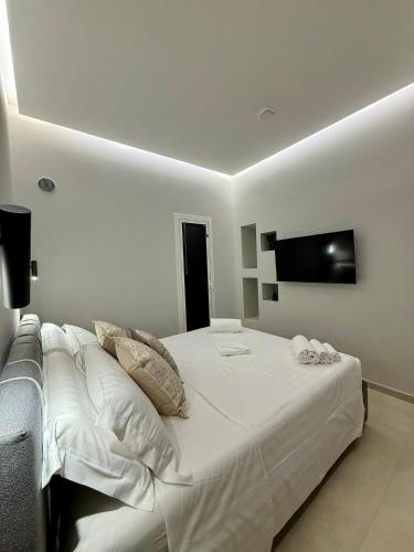a bedroom with a white bed with a flat screen tv at H Luxury Apartment Crispi in Olbia