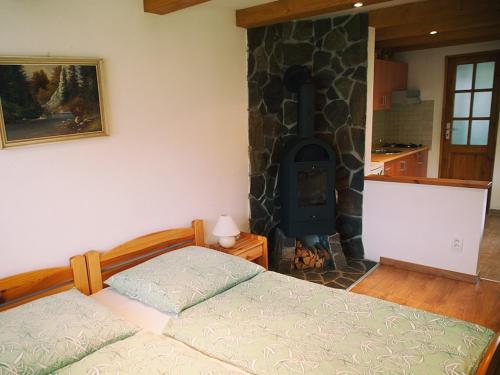 a bedroom with a bed and a stone fireplace at Zelená chalúpka a Zelený domček in Hrabušice