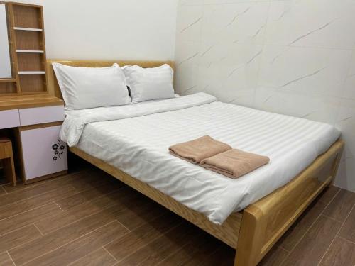 a bed with white sheets and a towel on it at Homestay Lê Thảo in Ấp Ða Lợi