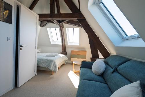 a living room with a blue couch and a bedroom at Le Presbytère in Ambleteuse