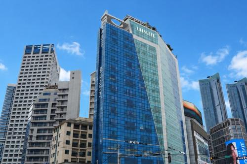 a tall glass building in a city with tall buildings at UH Suite The Haeundae in Busan