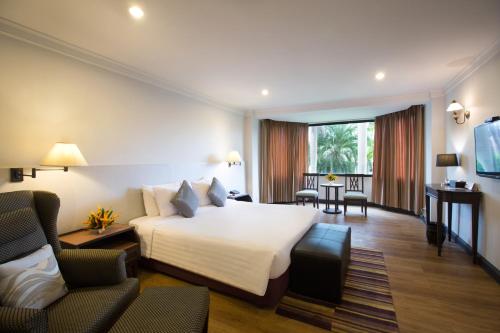 a hotel room with a bed and two chairs at The Imperial Hotel & Convention Centre Phitsanulok in Phitsanulok