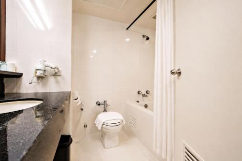 a white bathroom with a toilet and a sink at Lanna Palace 2004 in Chiang Mai