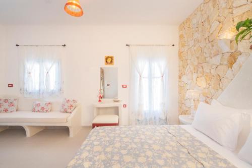 a white bedroom with a bed and a stone wall at Starlight Luxury Seaside Villa & Suites in Imerovigli
