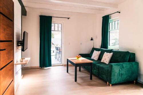 a living room with a green couch and a table at Domek Skowronek in Szczytna