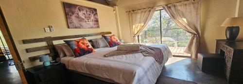 a bedroom with a bed with pillows and a window at Khoneni in Marloth Park