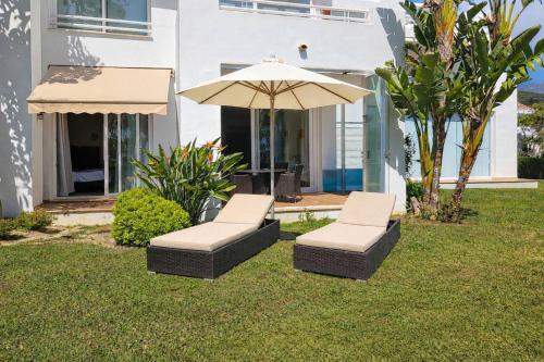 two chairs and an umbrella in the yard of a house at The Lagoon Apartment- Free Lagoon Access in Estepona