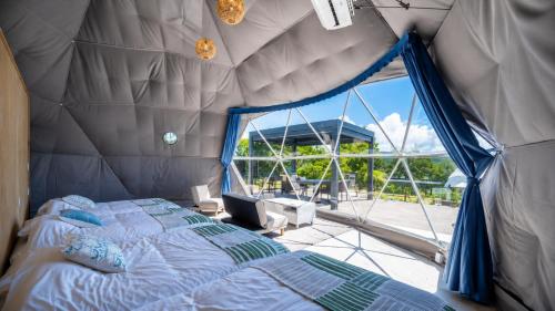 a bedroom with a bed and a large window at glampark Sesoko -Ocean Terrace- in Sesoko