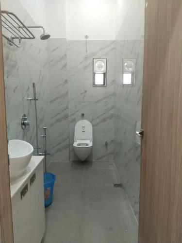 a white bathroom with a toilet and a sink at Hotel lakshmi in Goddā