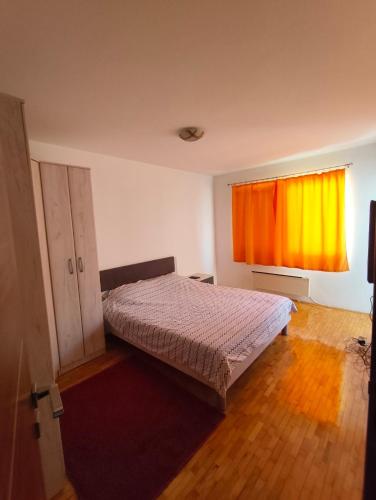 a bedroom with a bed and an orange curtain at Stan Foca N in Foča