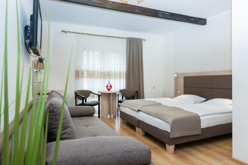 a bedroom with a bed and a couch and a tv at Paula Wellness & SPA in Pobierowo