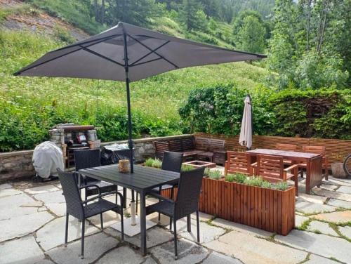 a table and chairs with an umbrella on a patio at Chalet a due passi piste da sci in Valgrisenche