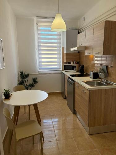 a kitchen with a white table and a white table and a table and chairs at AeraSuites Komárom in Komárom