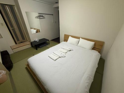 a bedroom with a large white bed with towels on it at アーバンホテル森下 in Tokyo