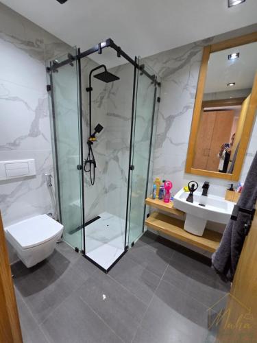 a bathroom with a shower and a toilet and a sink at Villa Triplex avec piscine proche de la mer in El Harhoura