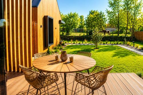 a wooden table and chairs on a wooden deck at Natur Harmony Tiszafüred in Tiszafüred
