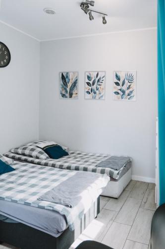 two beds in a white room with paintings on the wall at Motel Witnica in Witnica