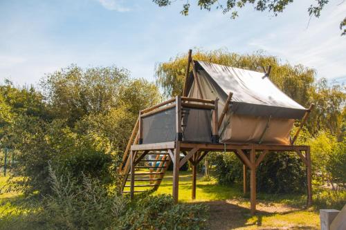 a tree house on a wooden stand in a field at Camping Haliotis in Pontorson