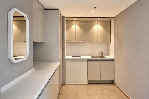a kitchen with white cabinets and a sink at Sun Cloud Hotel in Busan