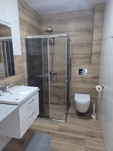 a bathroom with a shower and a toilet and a sink at Olimp Apartamenty in Konin