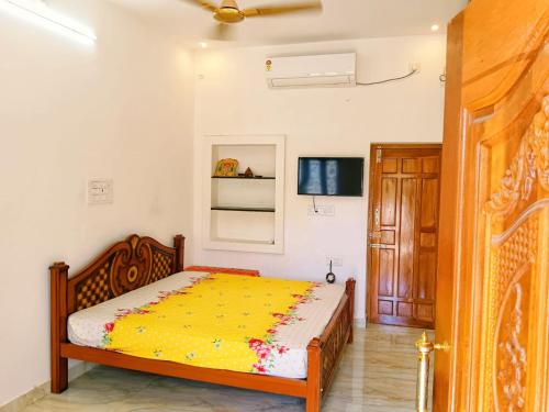 a bedroom with a bed with a yellow comforter at Sri Ram Villa in Rāmeswaram